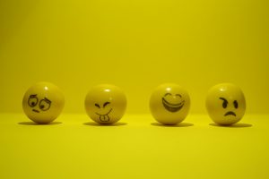 图片上有四个黄色的球，每个球上都画着不同的面部表情:担心、厚脸皮(吐舌头)、高兴(咧着嘴笑)和烦恼(耷拉着嘴，一只皱眉的眼睛)。