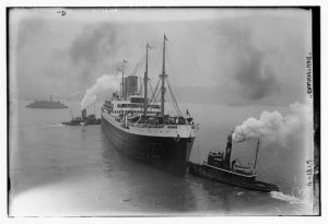 SS Deutschland号和两艘拖船的图片，烟囱冒出烟雾和蒸汽。