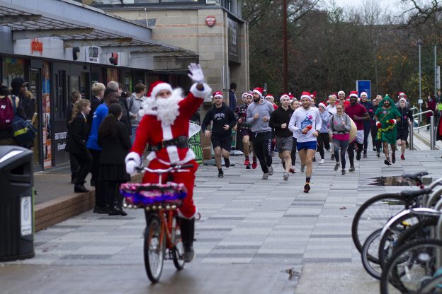 骑自行车和跑步的人打扮成圣诞老人
