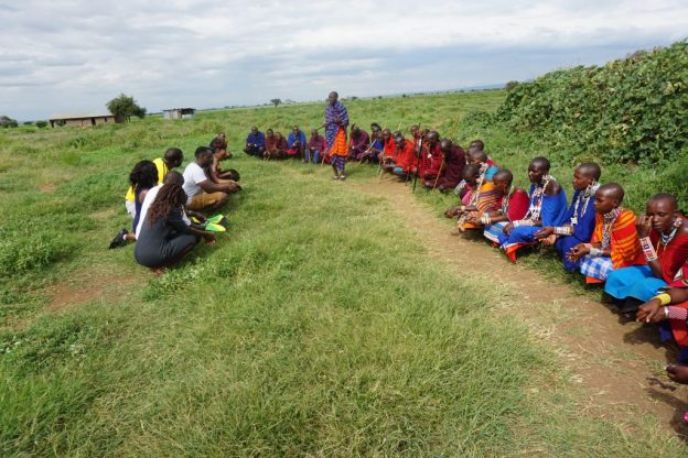 肯尼亚安博塞利马萨伊村的人们坐在草地上