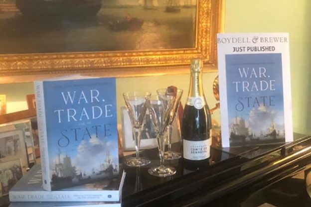 钢琴上放着两本《战争、贸易和国家》的书，还有一瓶香槟