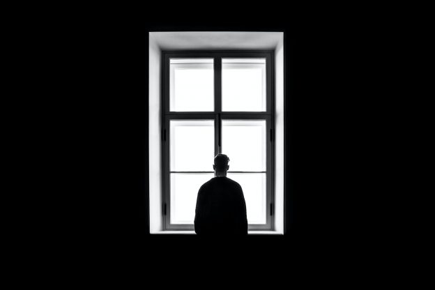 黑白照片的人站在看窗外从黑暗的房间