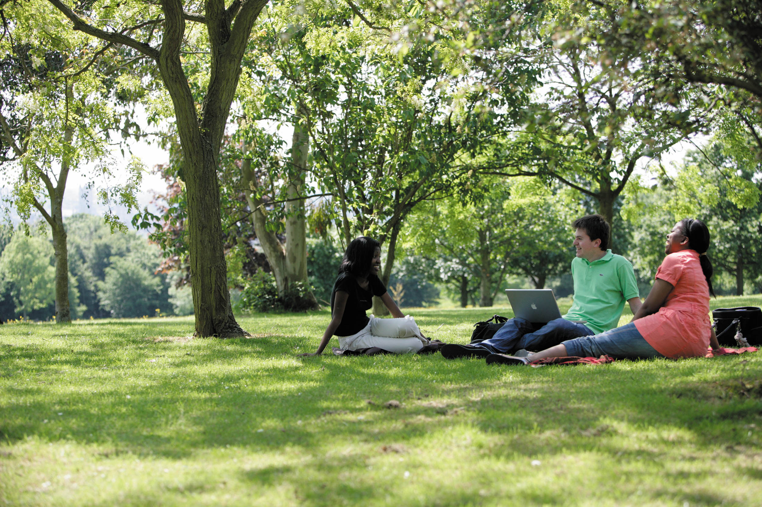 三个学生坐在草地上聊天